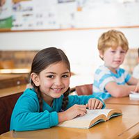 Young children in classroom reading books at a learning center.